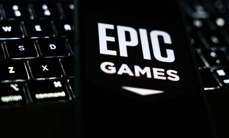 Epic Games logo displayed on a phone screen next to a laptop keyboard.