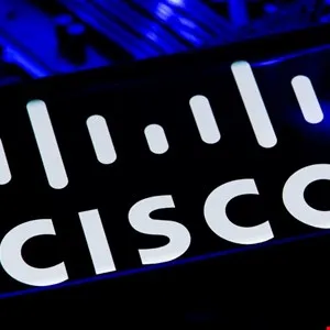 Close-up of the white Cisco logo against a dark, blue-lit background.