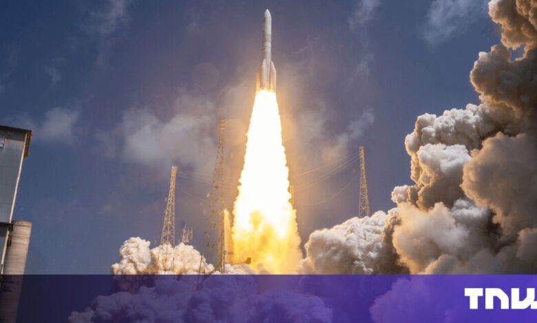 Rocket launching with bright flames and smoke against a blue sky.