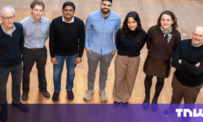 Group of eight diverse individuals standing on a wooden floor.