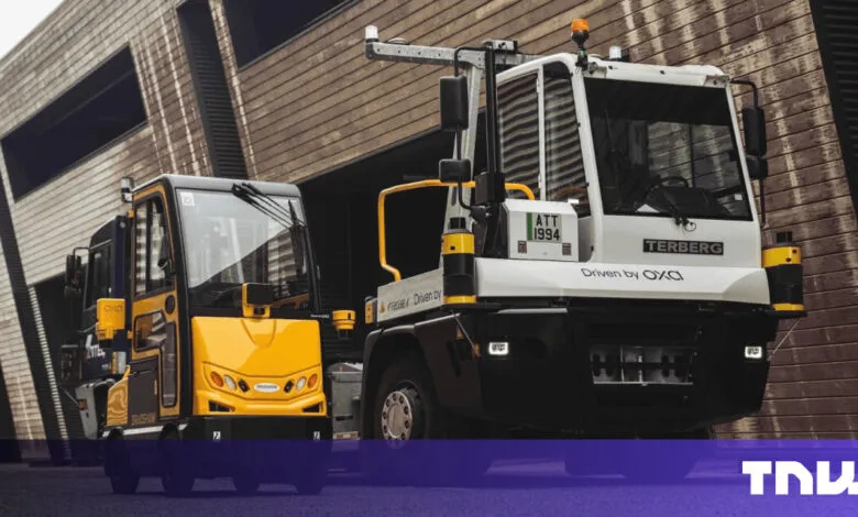 Two autonomous vehicles, a yellow Bradshaw and a white Terberg, stand outside a modern building.