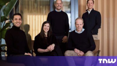 Group of five smiling professionals in a modern office setting.