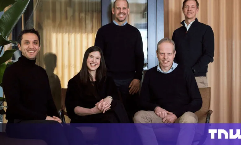 Group of five smiling professionals in a modern office setting.