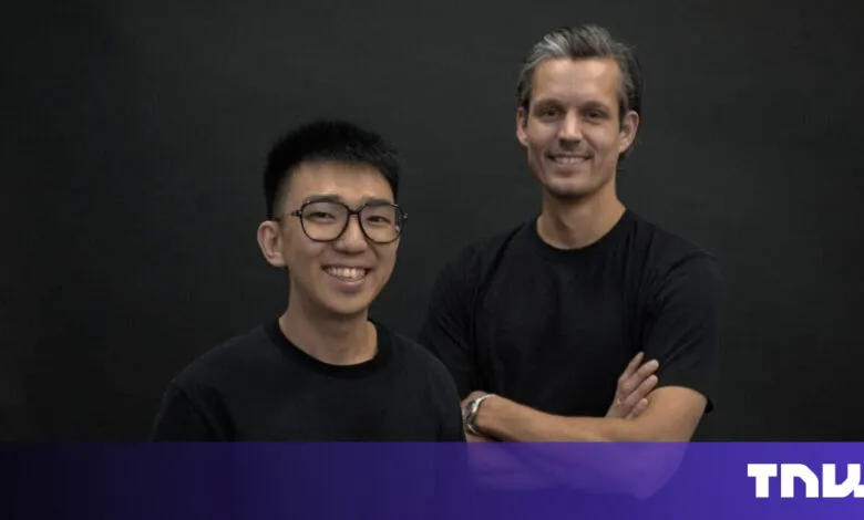 Two smiling men stand side-by-side against a dark background.
