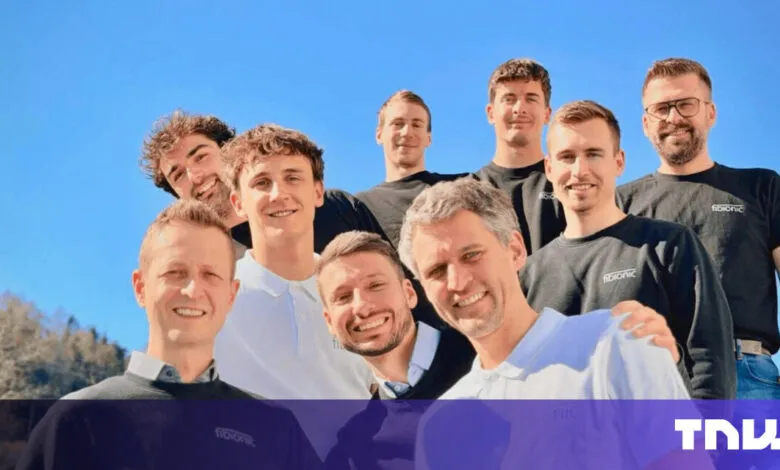 Group of nine smiling people outdoors under a clear blue sky.