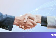 Two people in suits shaking hands against a light blue, networked background.