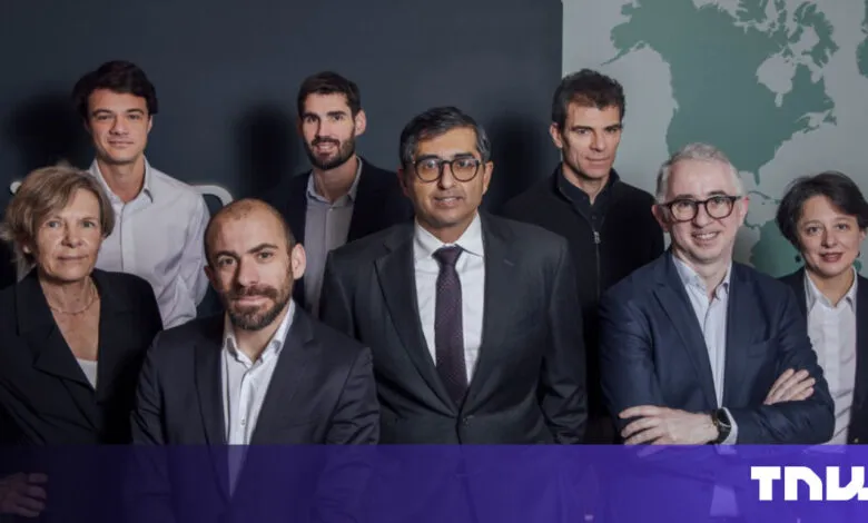 Group of nine professionals posing in front of a world map.