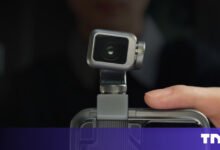 Compact camera attached to a smartphone, close-up view.