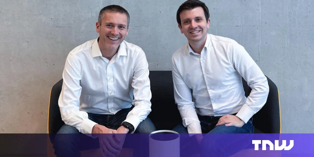 Two smiling men in white shirts sit side-by-side on a modern chair.
