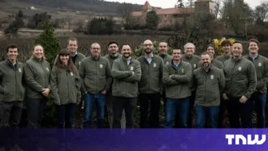 Group of people in matching jackets stand outdoors.