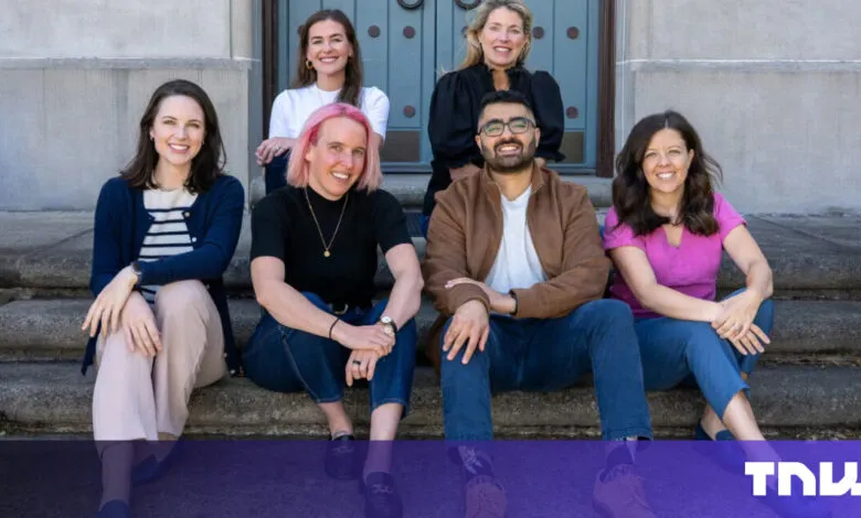 Group of six people sitting on stone steps, smiling at the camera.