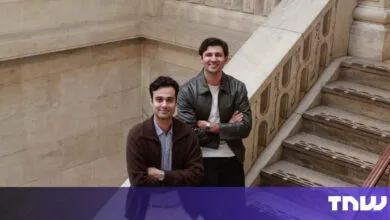 Two young men pose on marble staircase, smiling confidently.