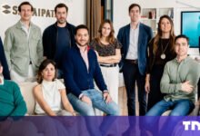 Group of diverse professionals posing in modern office setting.