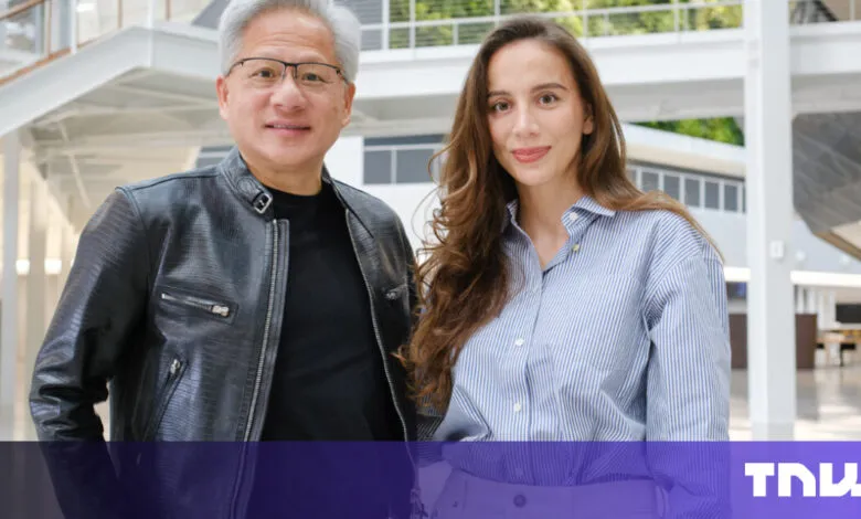 Jensen Huang, CEO of NVIDIA, poses with a woman in a modern building.