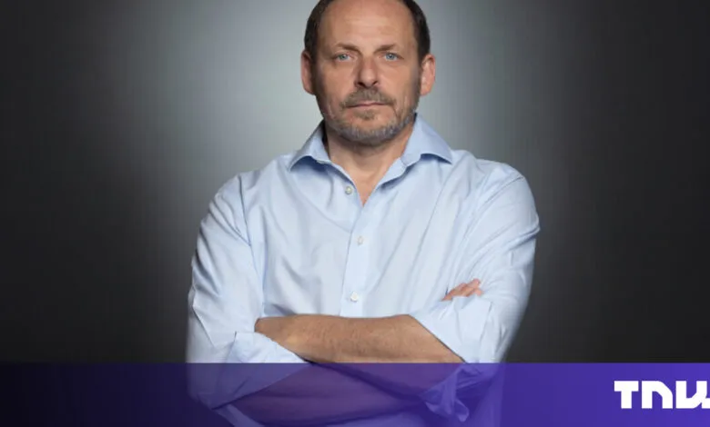 Portrait of a man with arms crossed against a gray background.