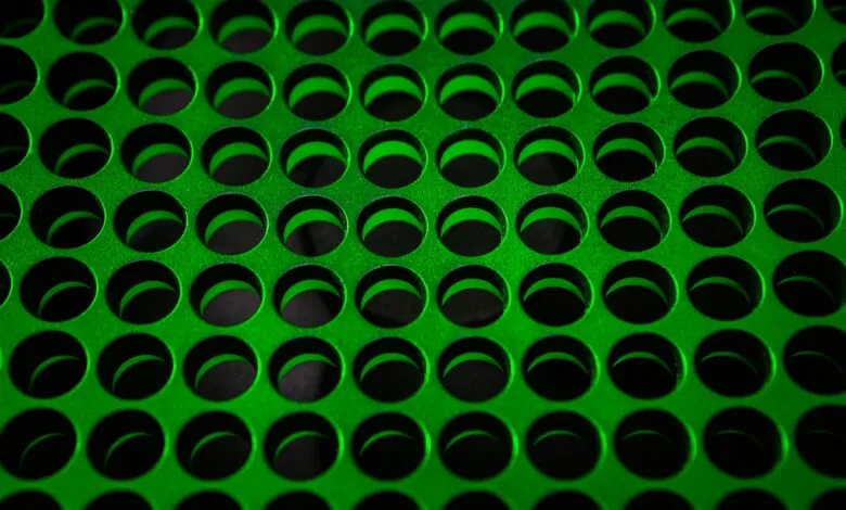Close-up of a green metal surface with a pattern of circular holes.