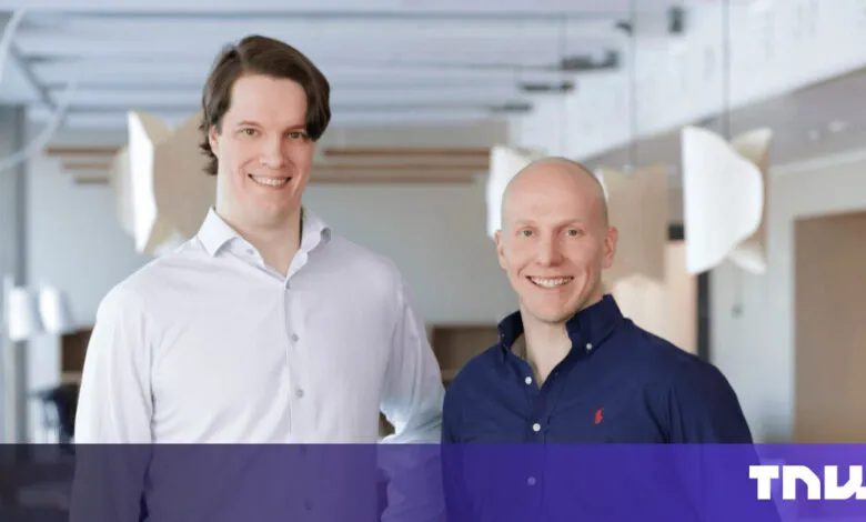 Two smiling men stand side-by-side in a modern office setting.