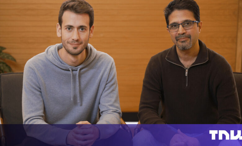Two men sit side-by-side in chairs, looking at the camera.