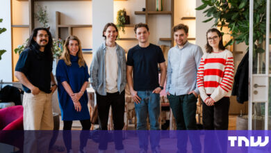 Group of six diverse young professionals smiling indoors.