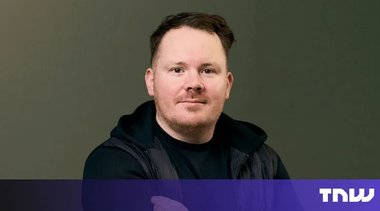 Headshot of a man with short brown hair and a black vest.
