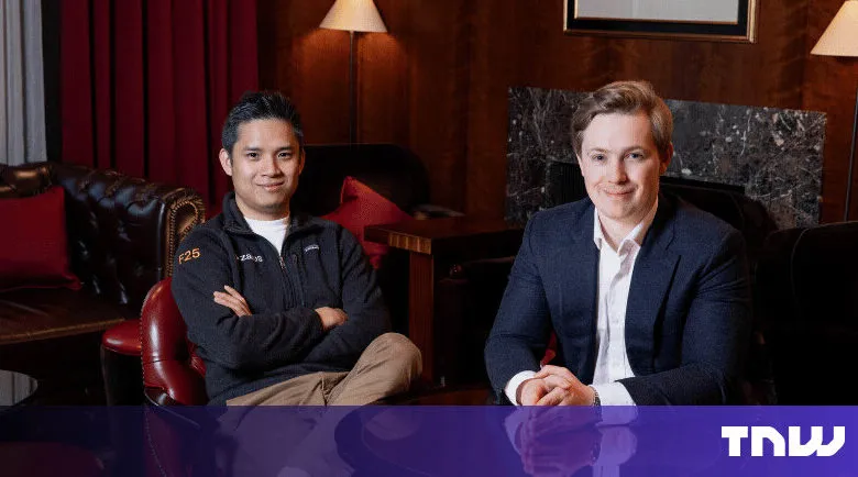 Two men pose indoors in a sophisticated setting.