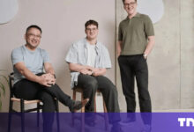 Three men pose indoors, seated and standing, in casual attire.