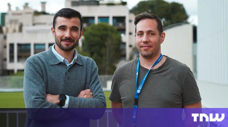 Two men stand side-by-side outdoors, smiling at the camera.