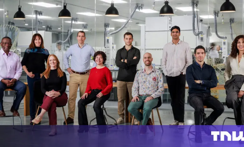 Diverse team of ten people posing in a modern laboratory setting.