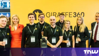 Group poses in front of Giraffe360 banner at event, smiling.
