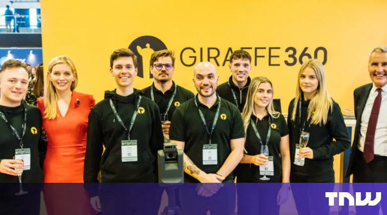 Group poses in front of Giraffe360 banner at event, smiling.