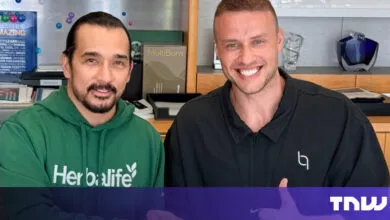 Two men smiling, one wearing Herbalife hoodie, the other a black jacket.