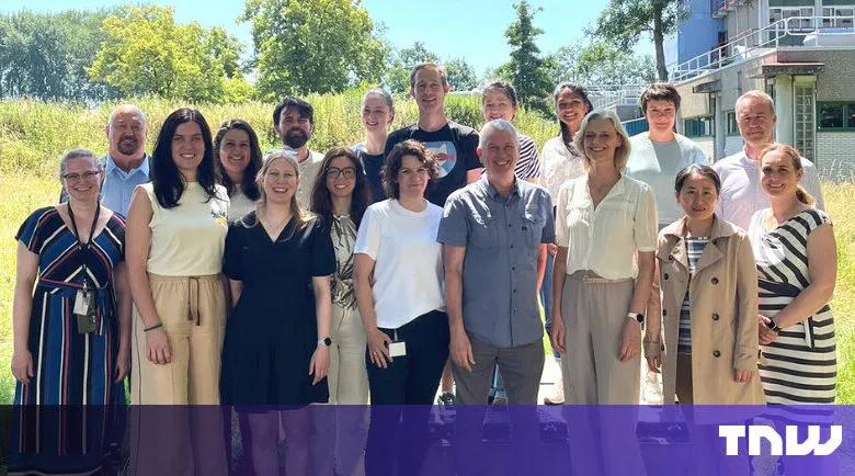 Group of diverse professionals pose outdoors for a team photo.