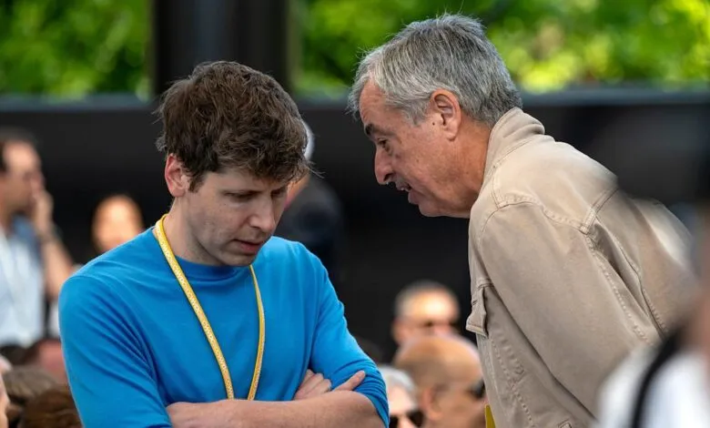 Two men in conversation, one in blue shirt with lanyard, the other in a tan jacket.