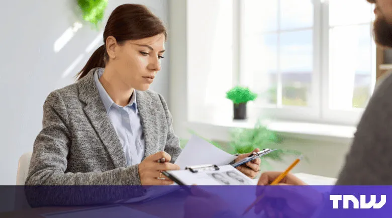 Woman in gray blazer reviews documents with a job applicant.
