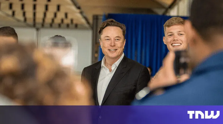 Elon Musk poses with fans for photos at an event.