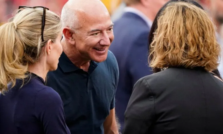 Jeff Bezos in conversation with two women at an outdoor event.