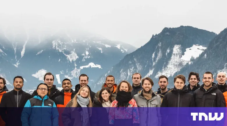 Group of people posing in front of snow-capped mountains.