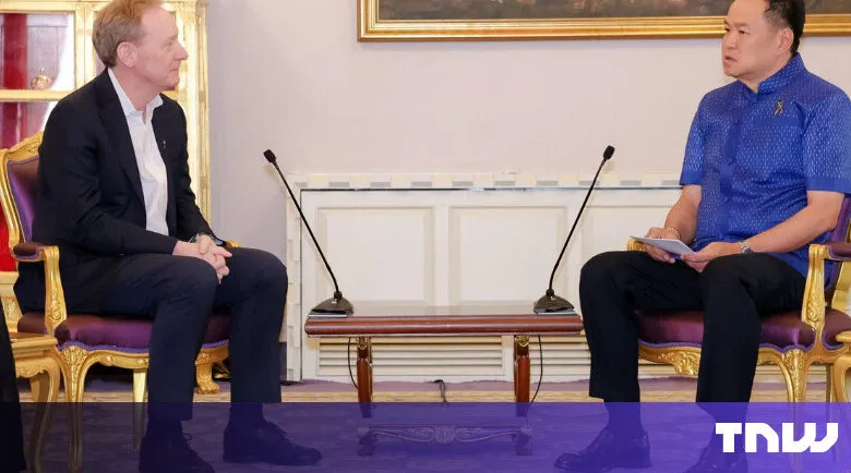 Two men sit facing each other in ornate chairs, microphones between them.