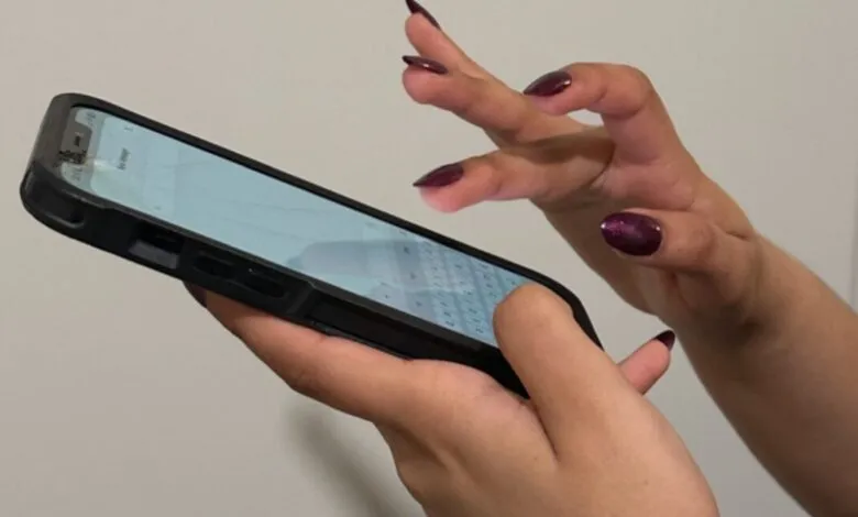 Hands with long, dark red nails typing on a smartphone.