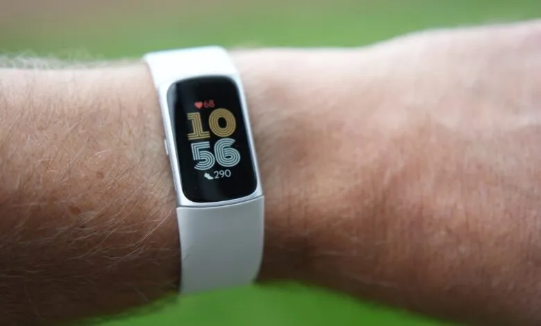 Fitbit Charge 6 on wrist displaying time 10:56, heart rate 68, and 290 steps.