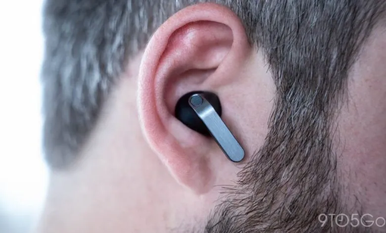 Close-up of black wireless earbud with silver accent in a person's ear.