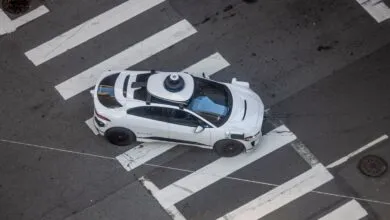 Aerial view of a white Waymo self-driving car crossing a street at a crosswalk.