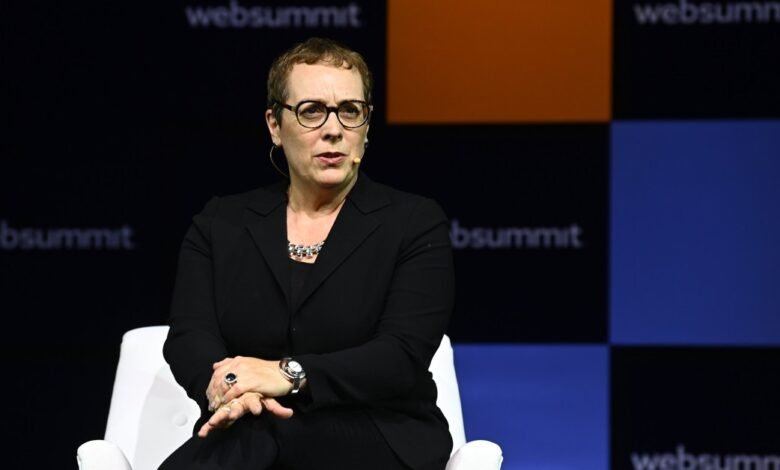 Woman with glasses sits in chair on stage at Web Summit conference.