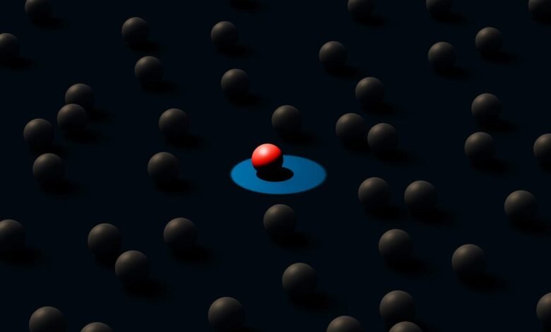 Red sphere stands out among gray spheres, highlighted by blue light.