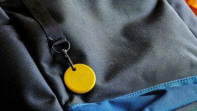 Yellow Chipolo tracker attached to a gray and blue backpack.