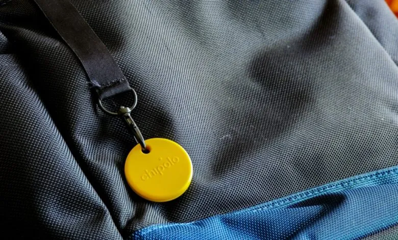 Yellow Chipolo tracker attached to a gray and blue backpack.