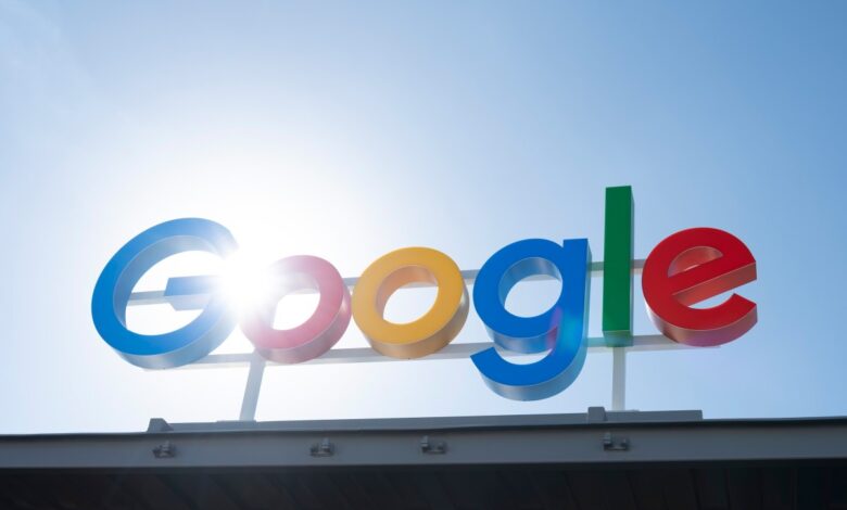 Google logo against a bright blue sky with sun flare.