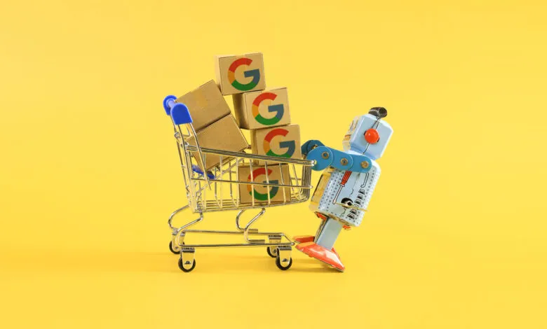 Toy robot pushing shopping cart filled with Google logo boxes.