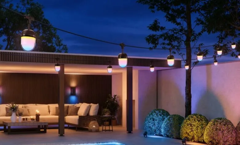 Outdoor patio with string lights, sofa, and pool at dusk.