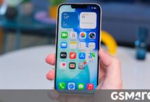 Close-up of iPhone screen displaying iOS home screen with various app icons.